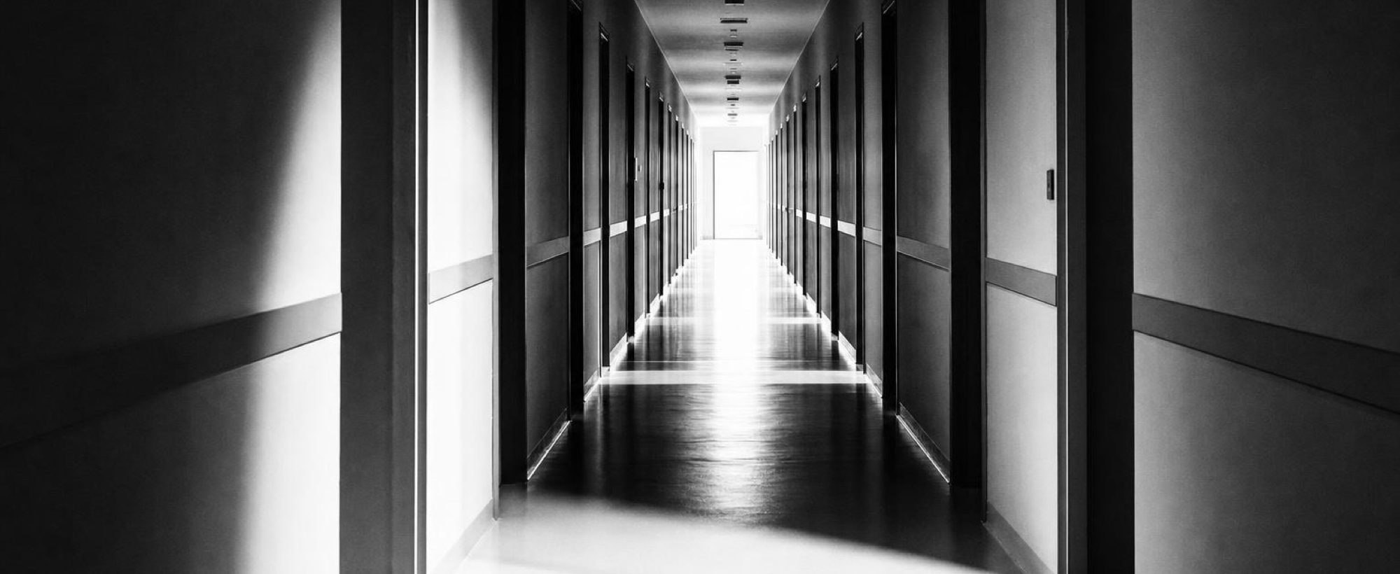 A hospital corridor running towards daylight at the far end