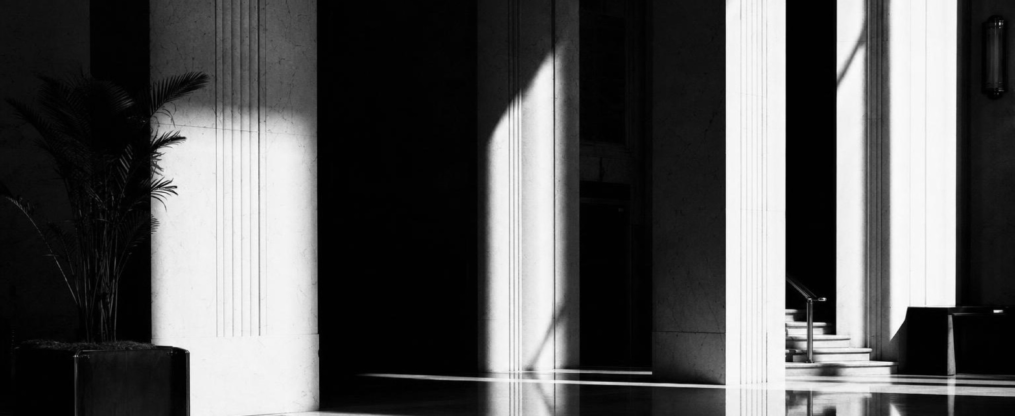 Light falling in hard shafts across a stone lobby