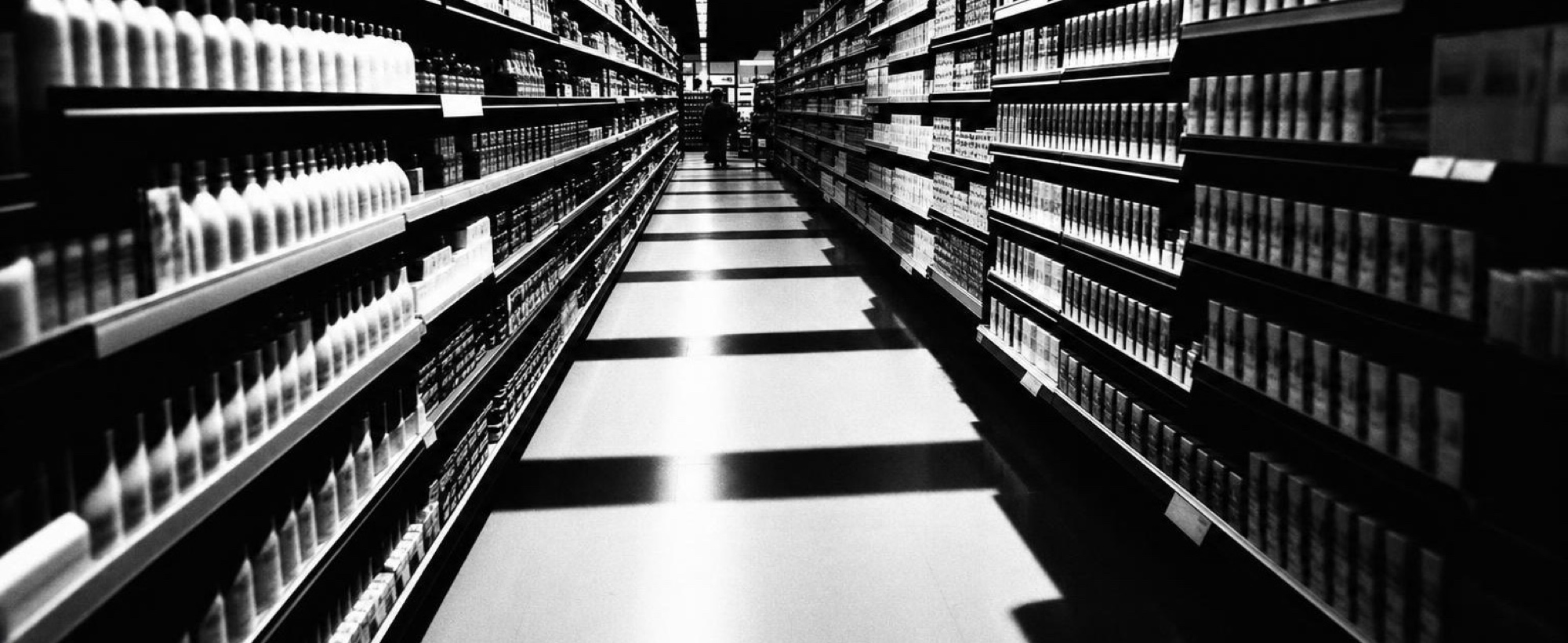 A supermarket aisle running between fully stocked shelves