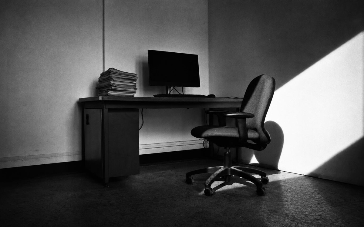 An empty desk with a monitor left on