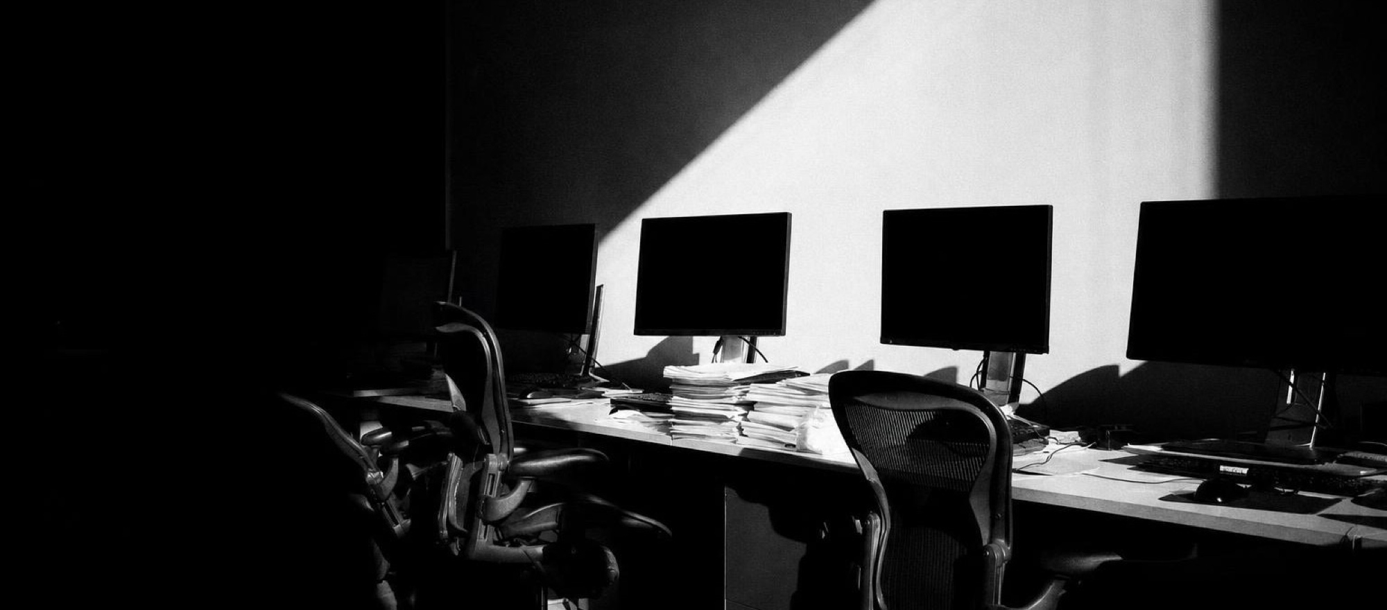 A dark office with the monitors still lit