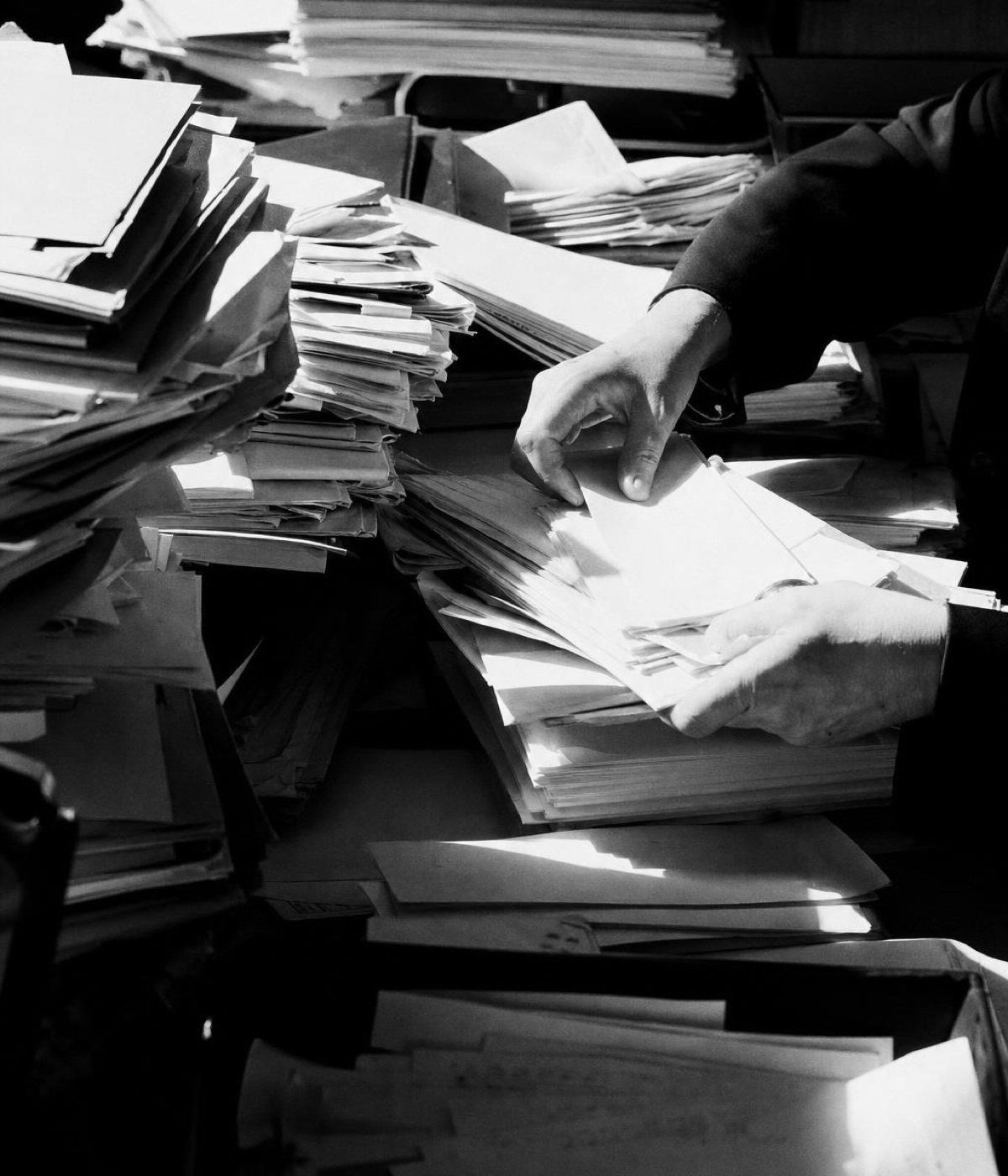 Hands sorting through piled patient folders