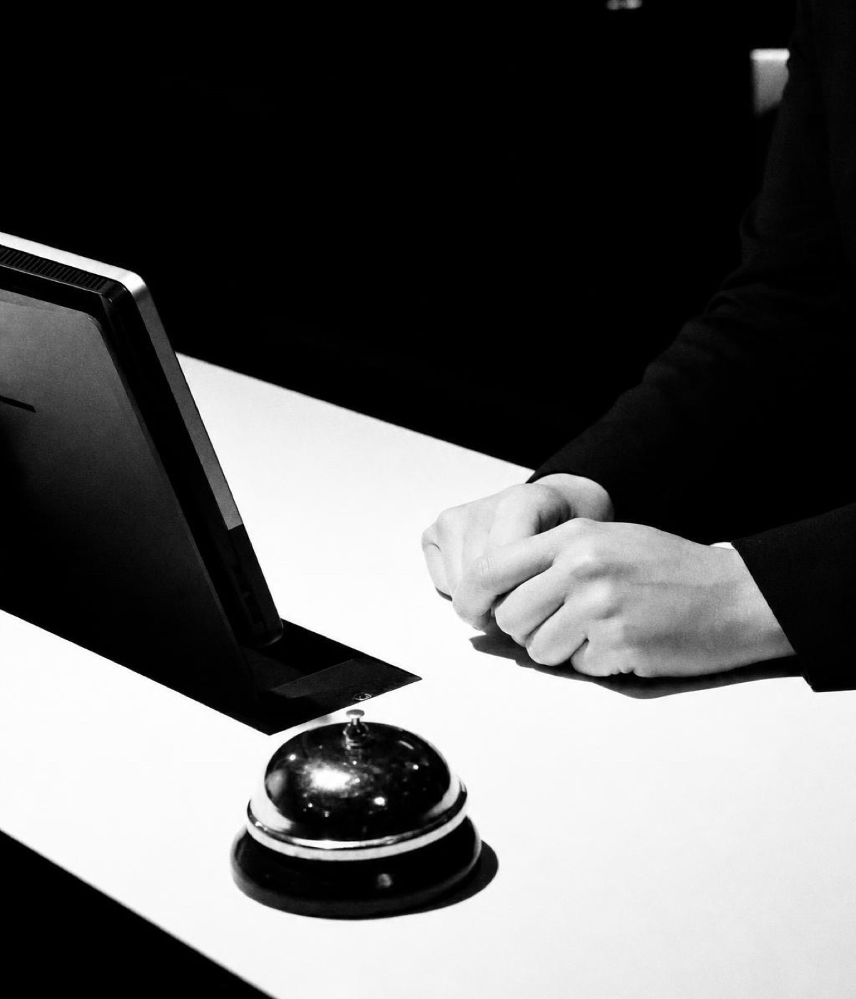 A closed laptop and a clenched fist resting on a desk