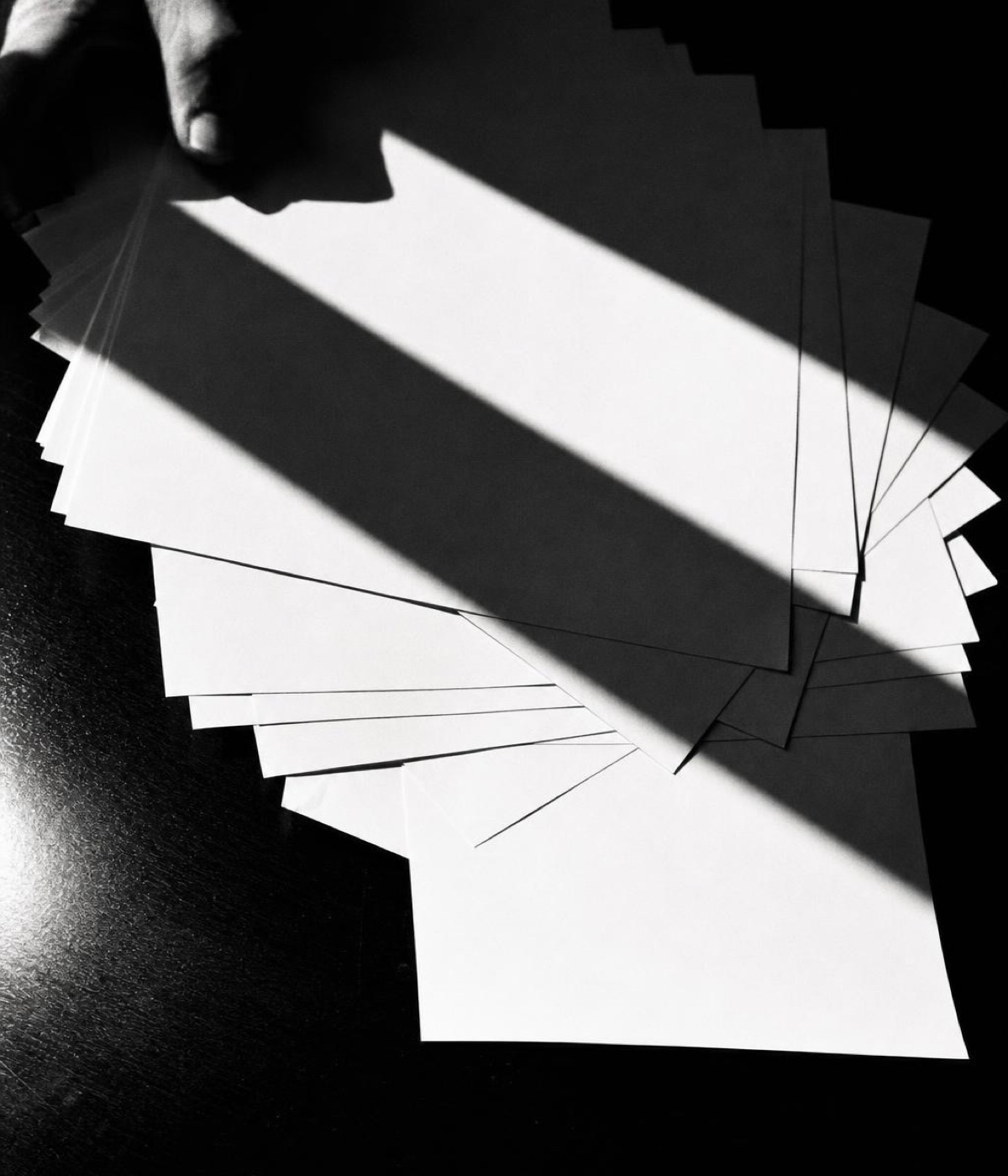 Loose sheets of paper scattered across a surface in hard light