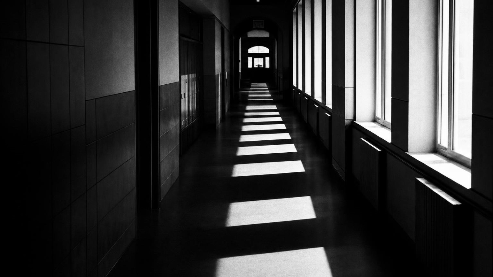A corridor striped with light from tall windows