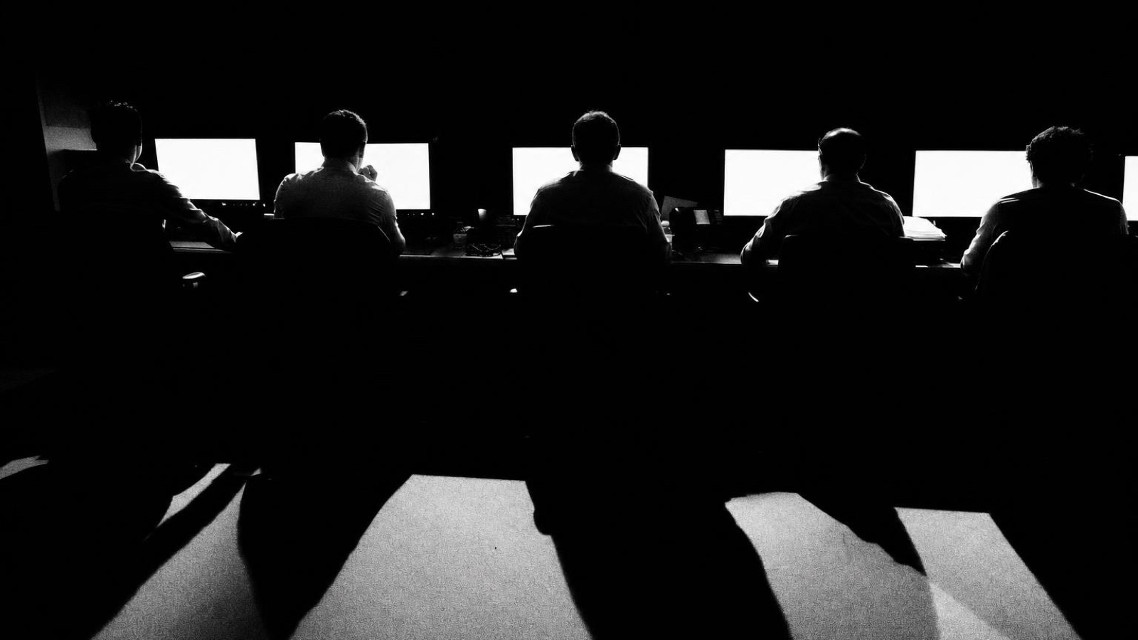 A row of people working along a lit window