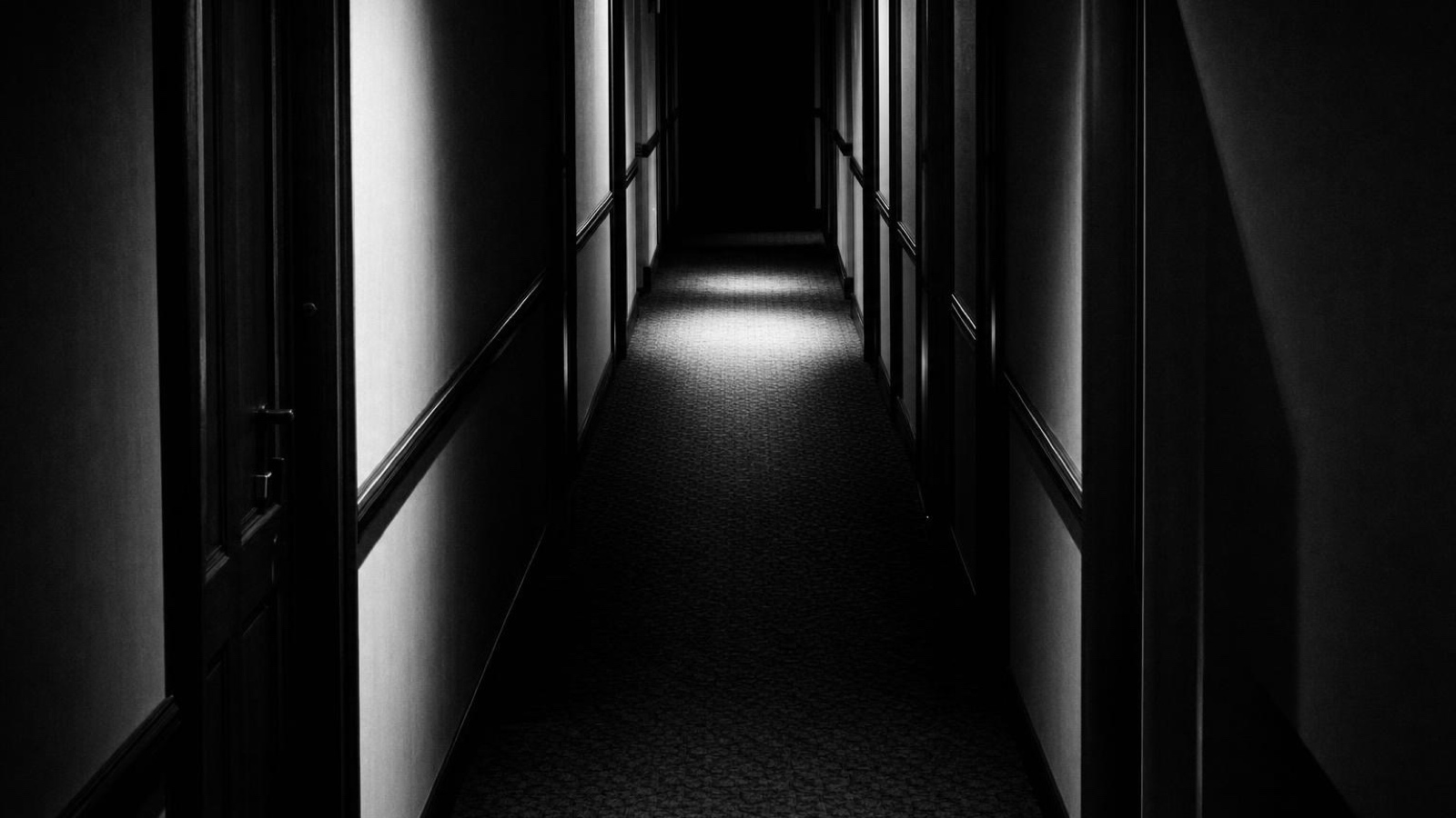 An empty corridor running towards a lit doorway